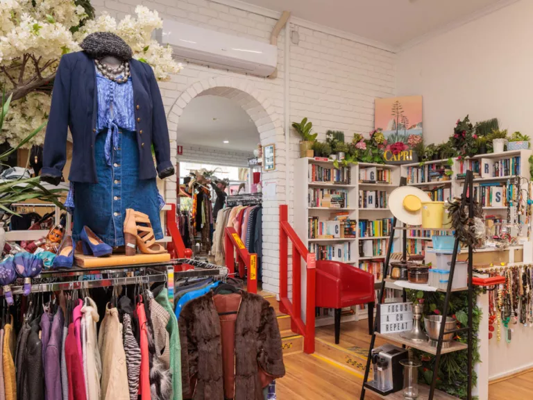 A store with clothes racks, a mannequin and shelves of books