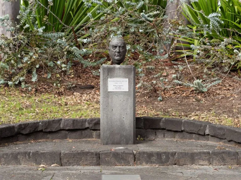 A small bronze head of a man with short hair. The head is attached to a rectangular column