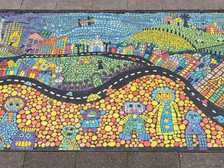 A colourful mosaic featuring smiling people, buildings and green hills