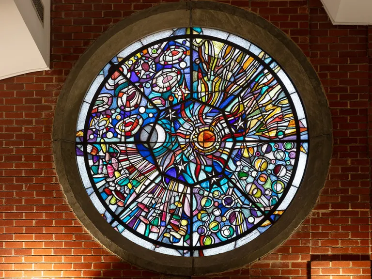 A circular stained glass window mounted into a brick wall