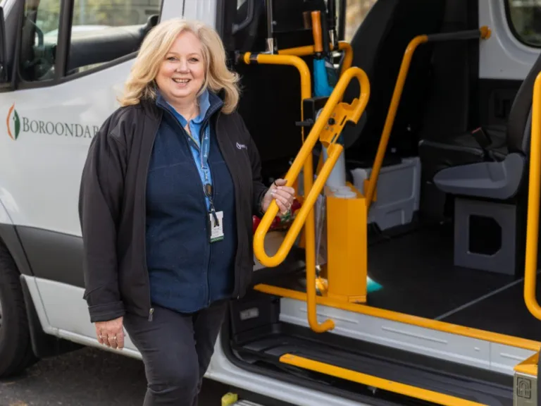 A woman standing next to an accessible entry door to a bus