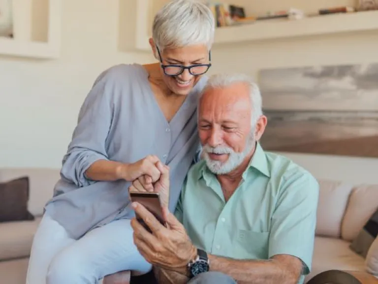 Older couple are looking at something on a mobile phone. 