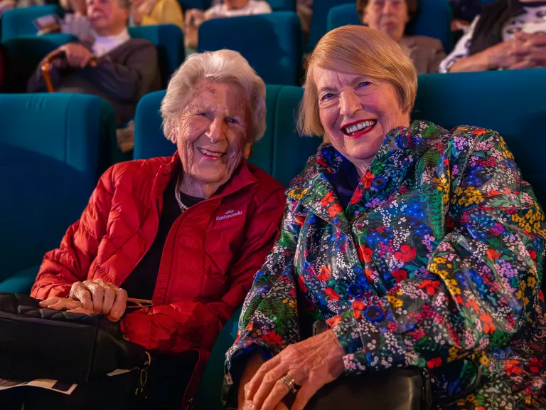 Two happy older women in bright jackets at the cinema