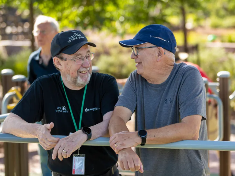 2 men over 50 chat amiably at a park