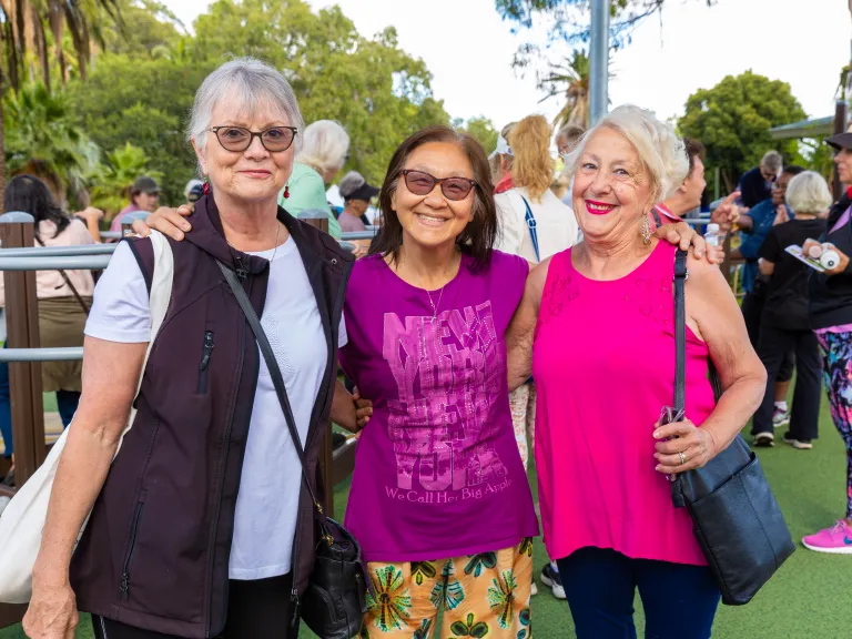 3 happy middle-aged women wearing bright colours at an outdoor setting