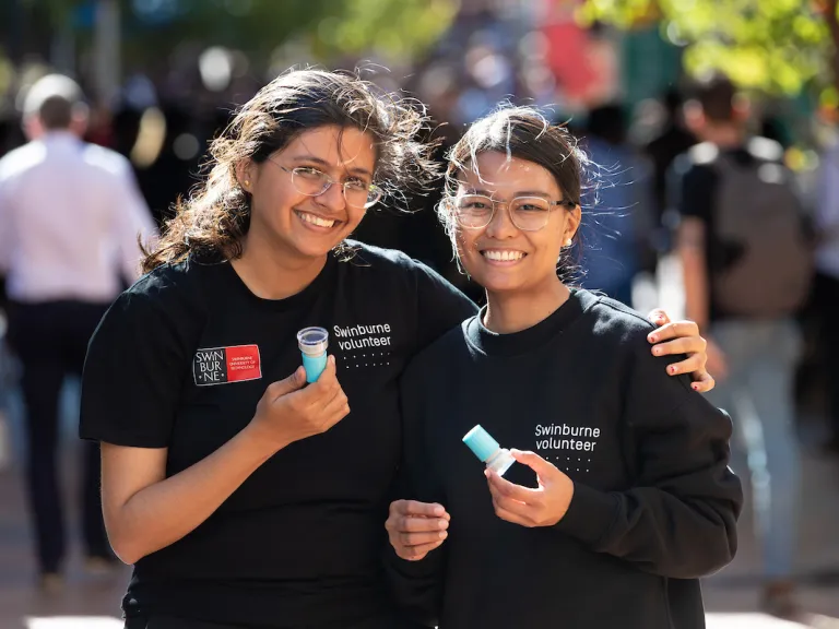 Two Swinburne University students smiling as they volunteer.