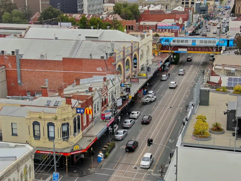 A busy high street with a train line passing overhead