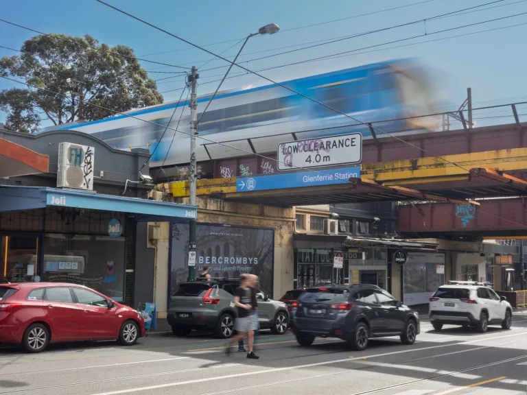 A train passes at speed on a bridge above a busy road
