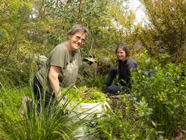 Two women smile while gardening.