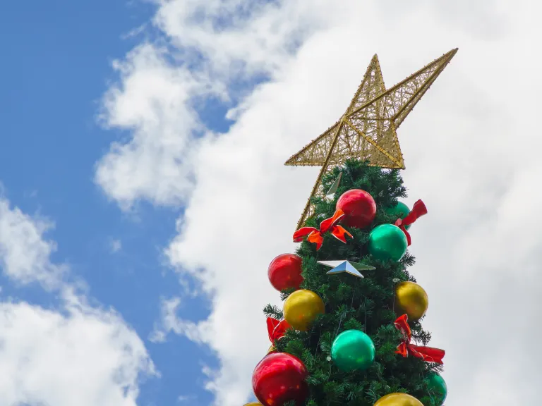 The top of a Christmas tree and large star against a partly cloudy sky