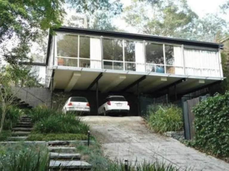 A mid-century heritage place. A home amongst trees, with 2 cars in the driveway.