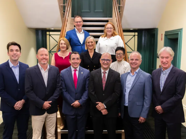 Council members posing for a group photo in Council office on stairs.