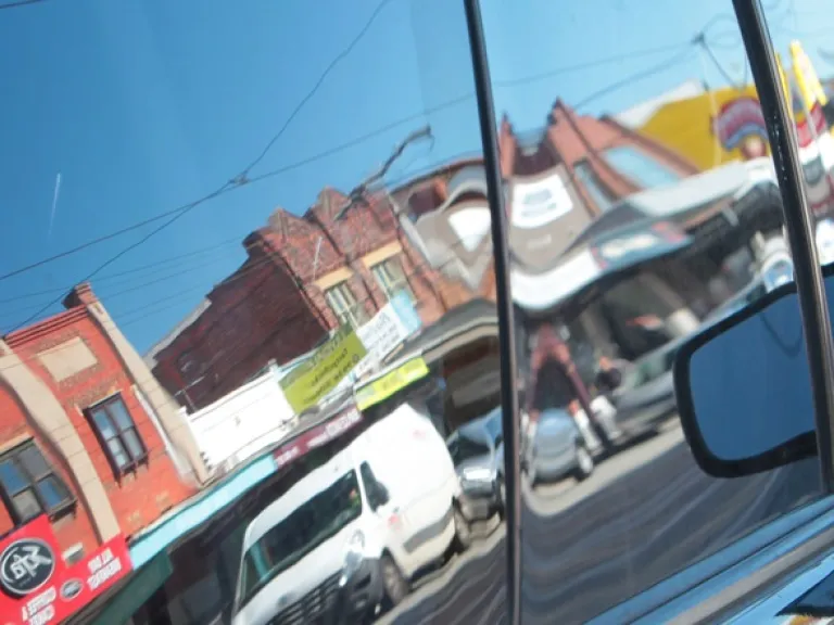 Reflection of a row of shops in a car's windows.