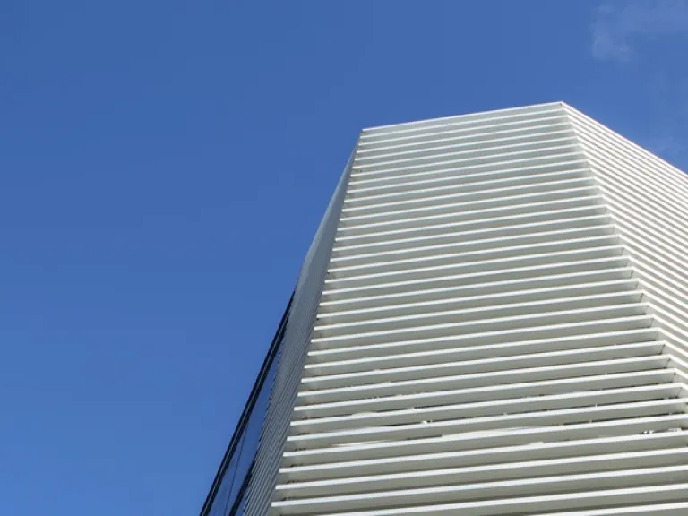 Looking up at an angular apartment building against a blue sky