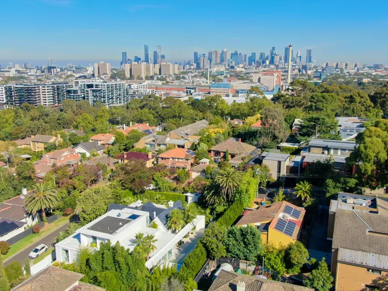 Birds eye view of a leafy suburb with many houses and the city skyline in the distance