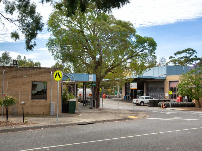 2 brick buildings separated by a road surrounded by trucks. trees and stacked tyres
