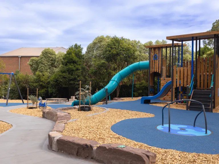 A small playground with a timber play unit, enclosed slide and balancing unit 