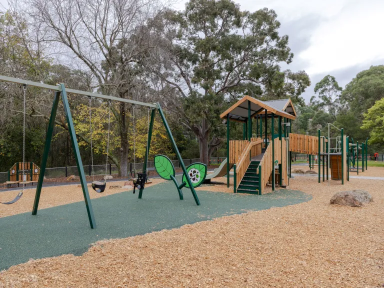 Three swings and a timber climbing unit at a playground