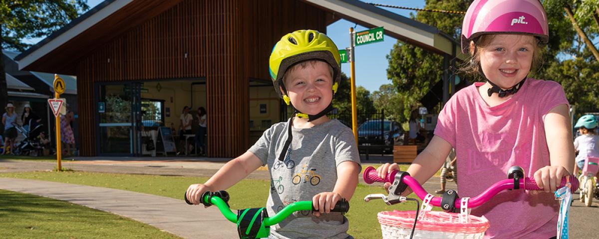 A boy and girl on their bikes smile at the camera at Kew Traffic School