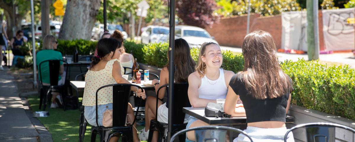 Two women sit at one of Boroondara's parklets and talk