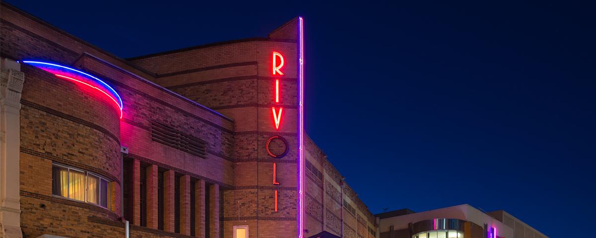 The Rivoli Theatre at night with its neon signs lit up