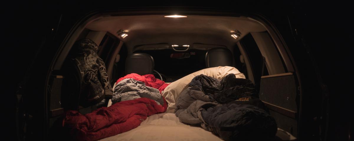 An open car boot with a large flat area where two sleeping bags are shown inside the car