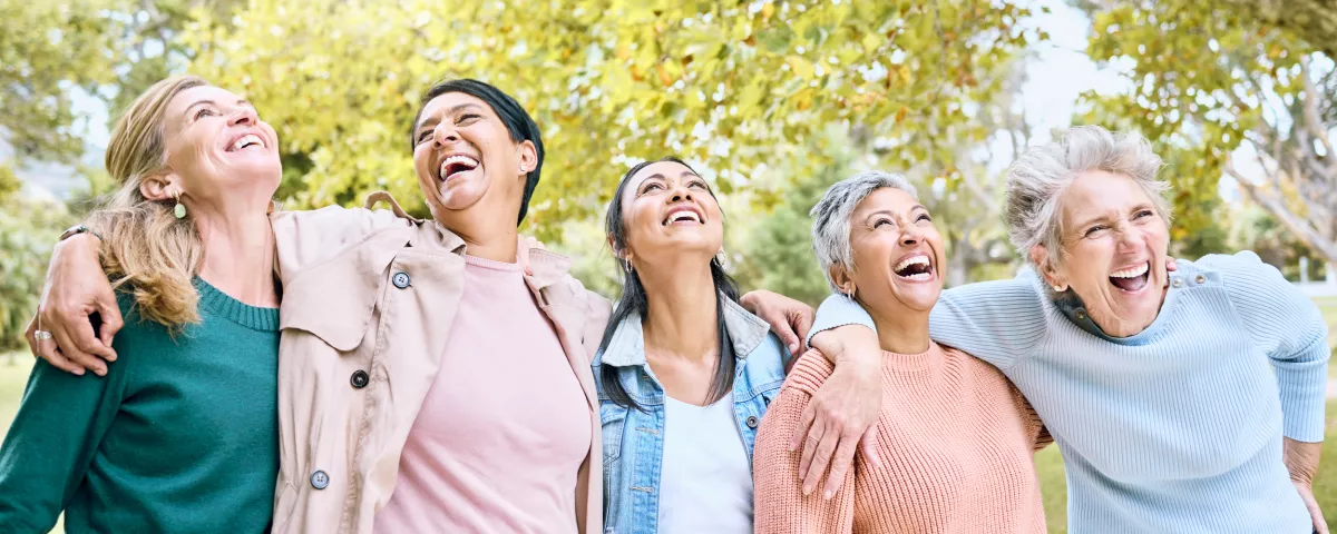 Five older women lined up in a park laughing