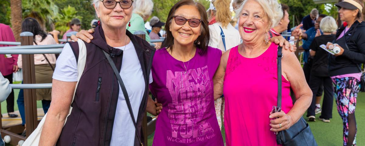 Three women with their arms around each other at an event 