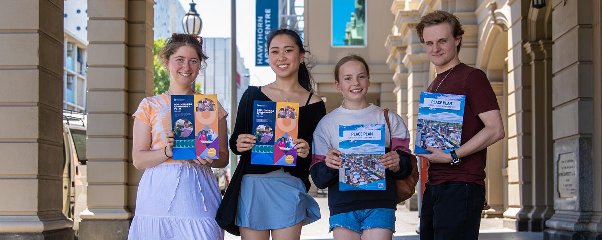 Four smiling young people holding copies of Glenferrie Place Plan at Hawthorn Arts Centre
