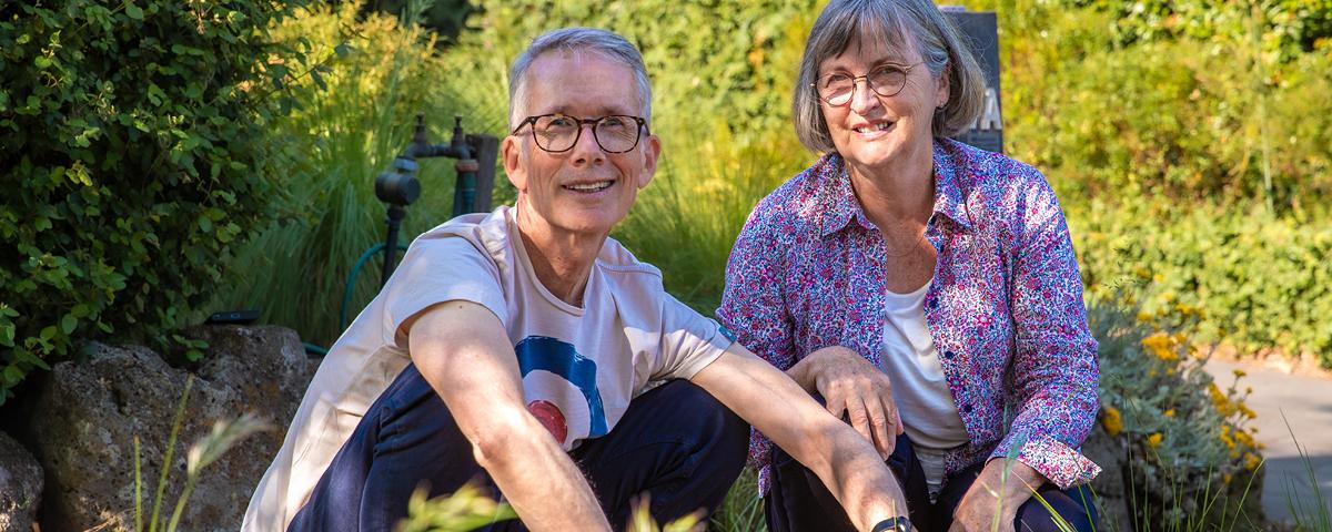 Botanist Tim Entwisle and Lynda Entwisle crouching beside nature strip with tufts of plants in foreground.