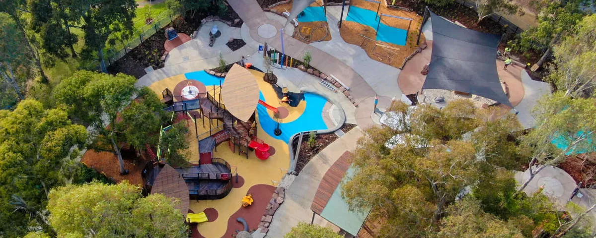 A birdeye view of a large playground surrounded by trees 