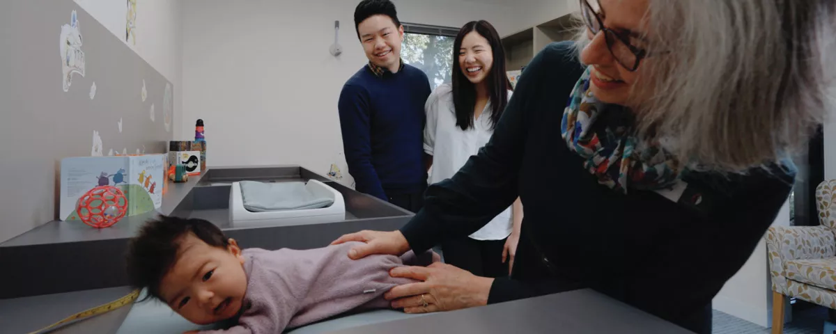 Nurse holds baby with parents in background
