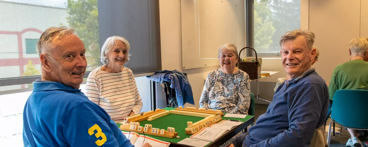 Four people play a board game around a table at the Camberwell Community Centre.