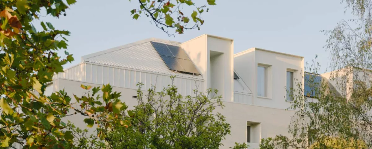 The top floor of a white house surrounded by trees