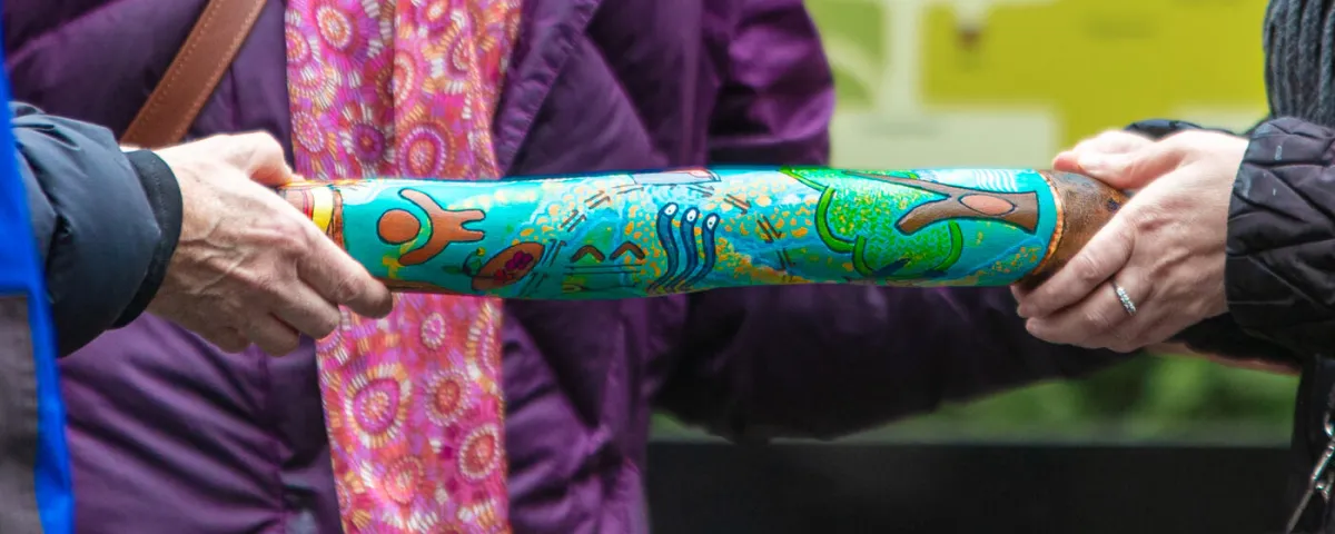 Two people holding a thick stick covered in illustrations