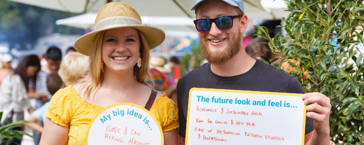 2 people outside looking at the camera holding signs with handwriting on them