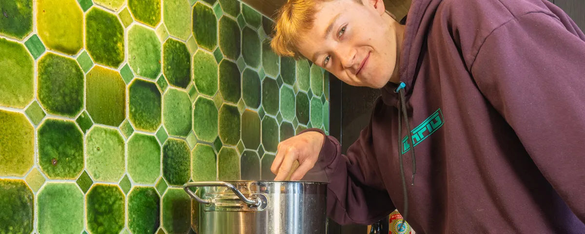 Teenager stands stirring pot on induction stove