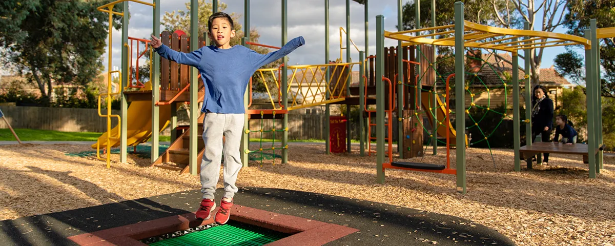 Child bounces on trampoline at playground