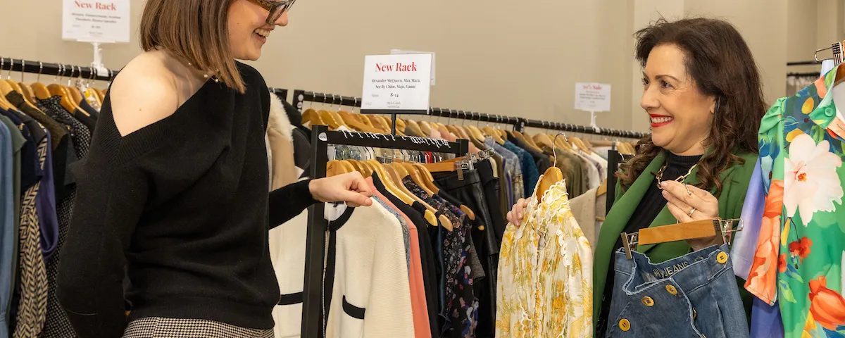 2 people looking through a rack of clothing
