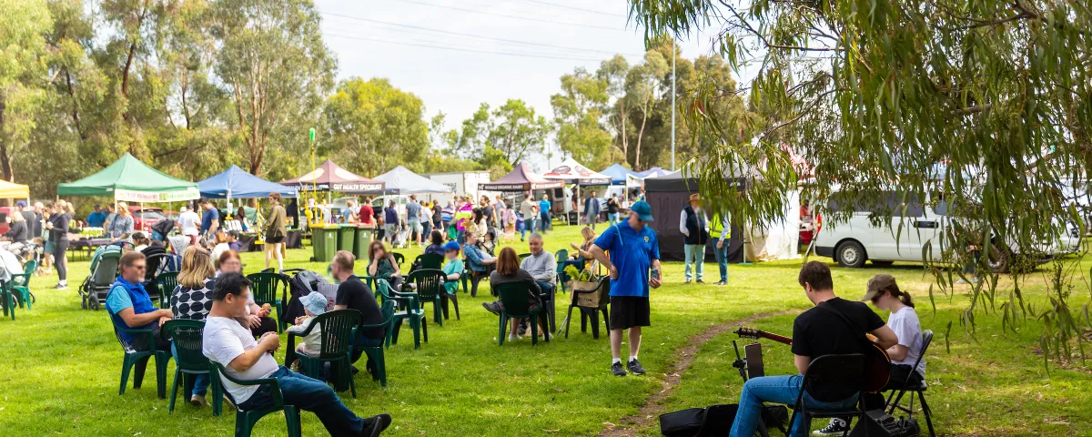 a large grassy area with scattered chairs and market stalls.