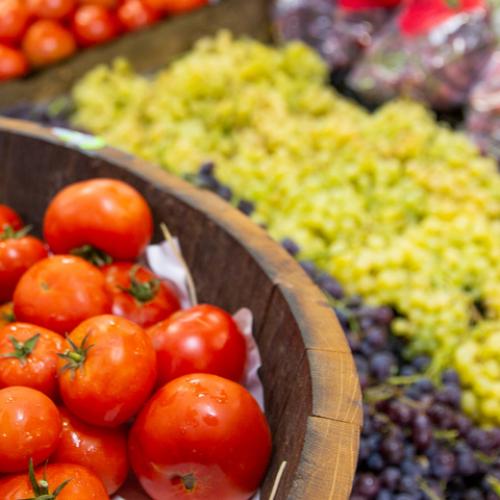 Fresh food market stall with red tomatoes and green grapes