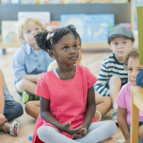 A group of children listening to a book being read by an adult