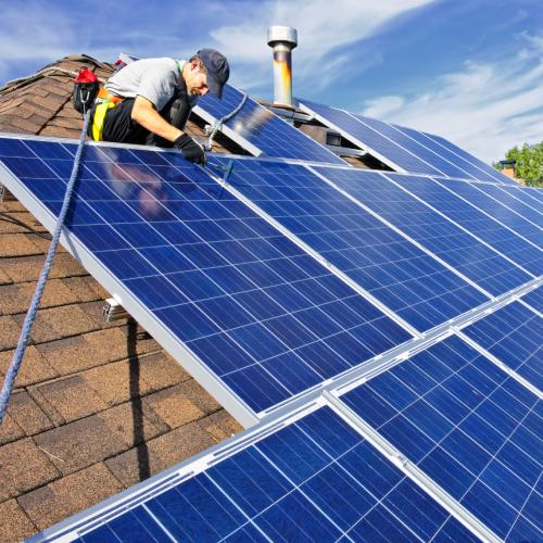 A man is on a roof installing solar panels