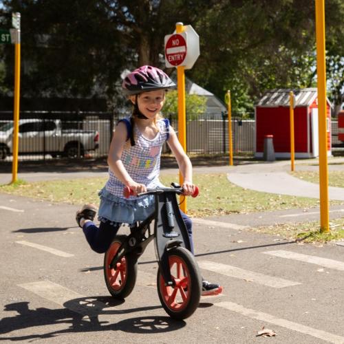 Young child happily riding a bike on the roads at the Kew Traffic School