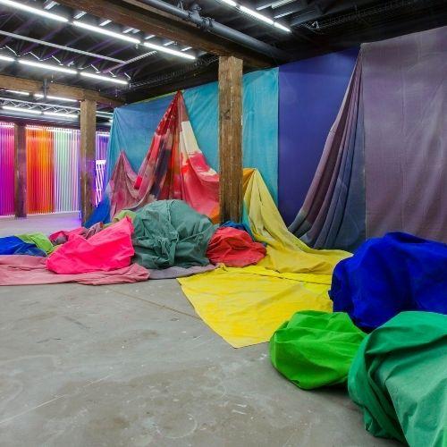 large sheets of canvas painted with bright colours and draped across the walls and piled on the ground