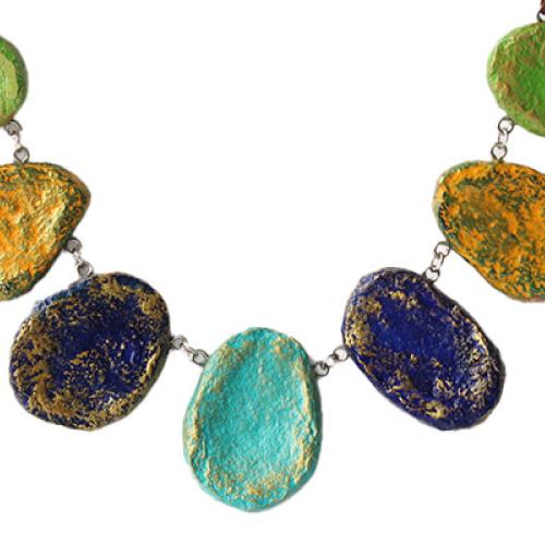 A necklace with 7 pendants in a range of green and blue colours, made from paper mache