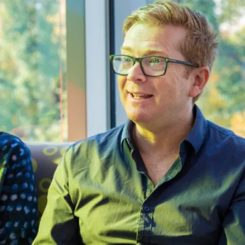 Three people sitting in a row chatting to each other at a workshop