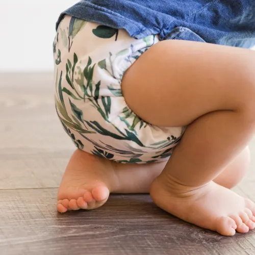 a baby wearing a reusable cloth nappy crouching