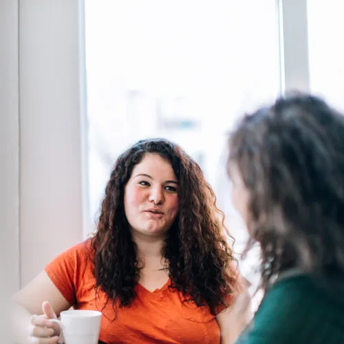 Two women have a cup of tea together.