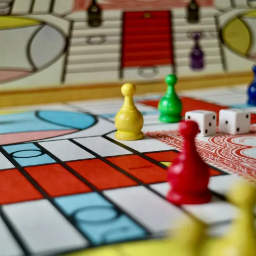 Colourful game pieces and a dice sit on a board game.